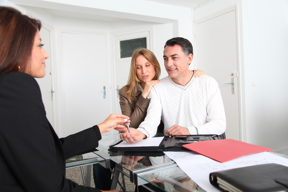 Couple signing property contract with real estate agent